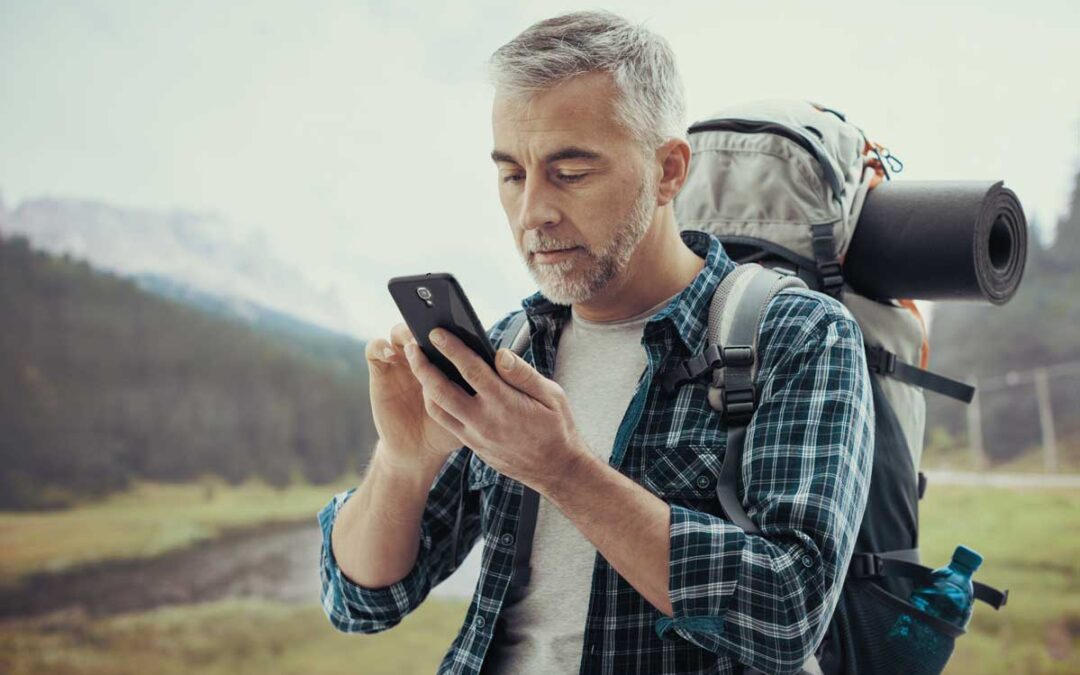 Older man on a hike using his smartphone to access Digital Banking