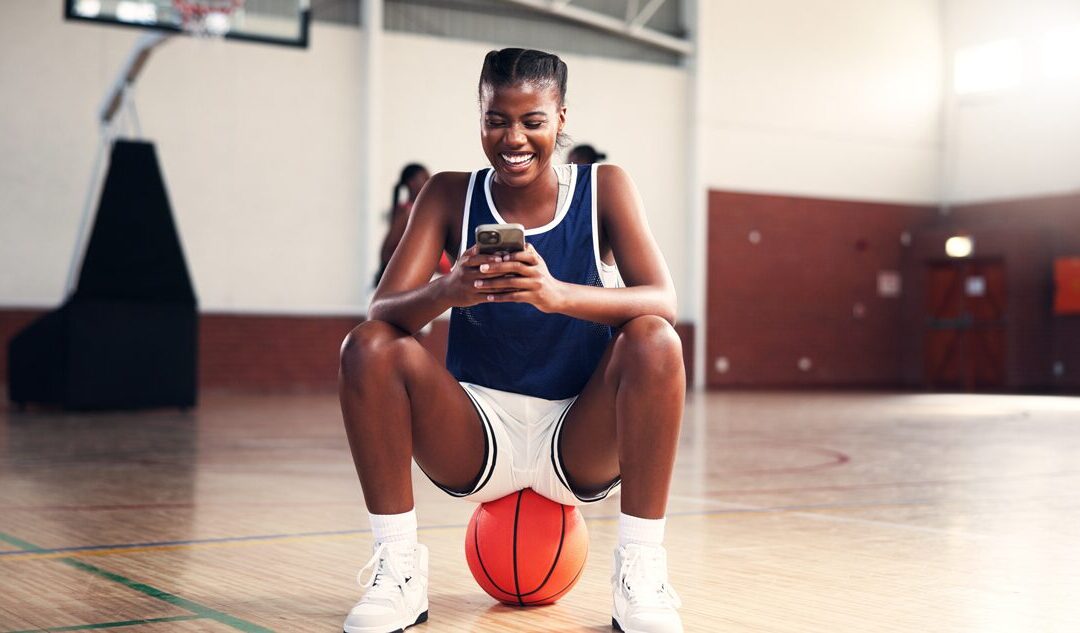 Basketball player checking their phone to see they got Paid Early with NET's Direct Deposit.